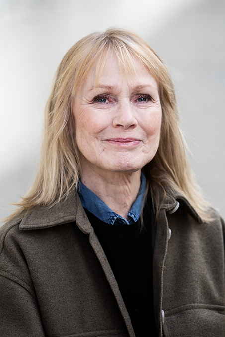 Portrait picture of Tone Helly-Hansen, company host. Tone has straight blond hair with bangs, jeans shirt with a black sweater on top and over that a grey wool coat. Photo: Polina Ulianova